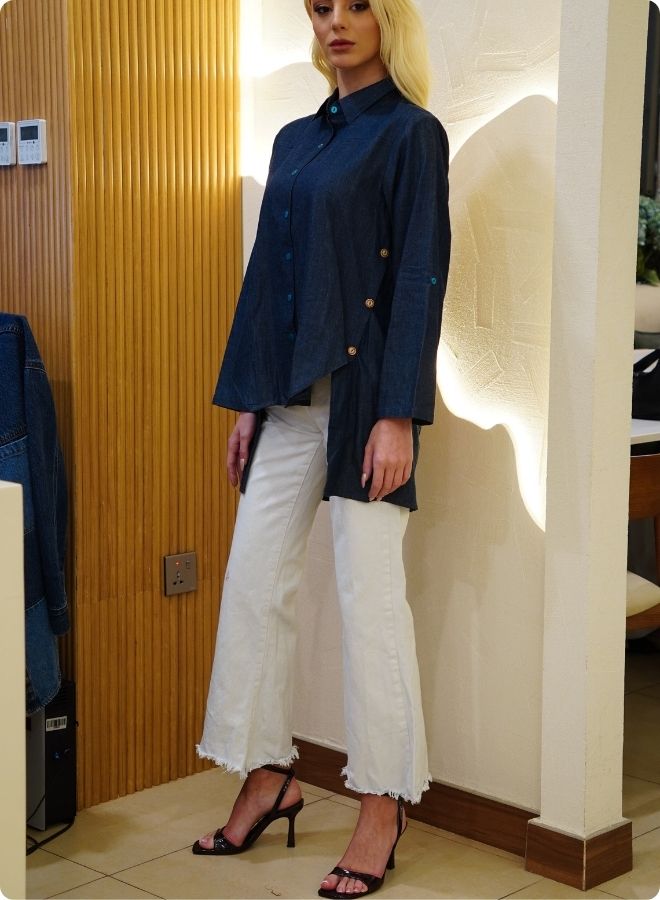 Denim blue in sturdy washed cotton shirt with collar and button down front and high low hem with embroidery at the back