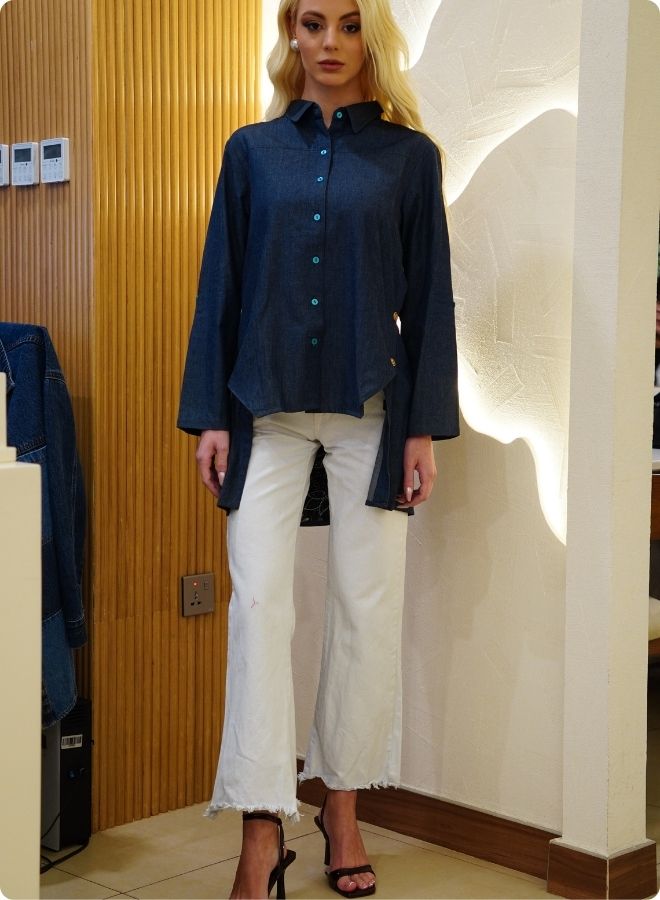 Denim blue in sturdy washed cotton shirt with collar and button down front and high low hem with embroidery at the back