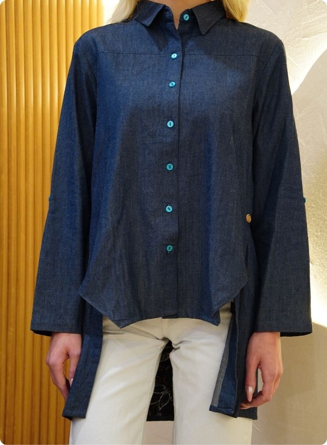 Denim blue in sturdy washed cotton shirt with collar and button down front and high low hem with embroidery at the back