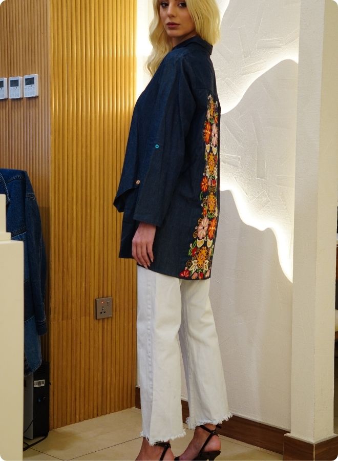 Denim blue in sturdy washed cotton shirt with collar and button down front and high low hem with embroidery at the back