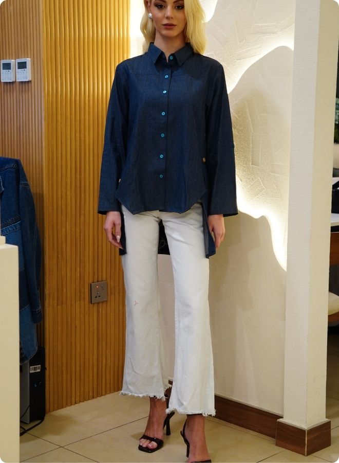 Denim blue in sturdy washed cotton shirt with collar and button down front and high low hem with embroidery at the back