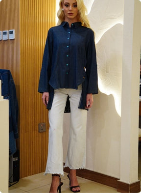 Denim blue in sturdy washed cotton shirt with collar and button down front and high low hem with embroidery at the back